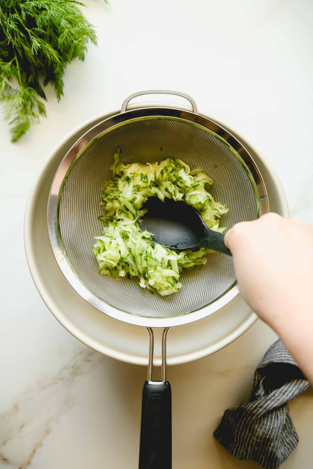 Shredded Cucumber in a Strainer Pressed with a Spoon
