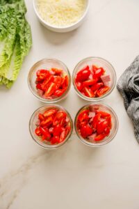 Add ¼ cup of tomatoes to each jar.