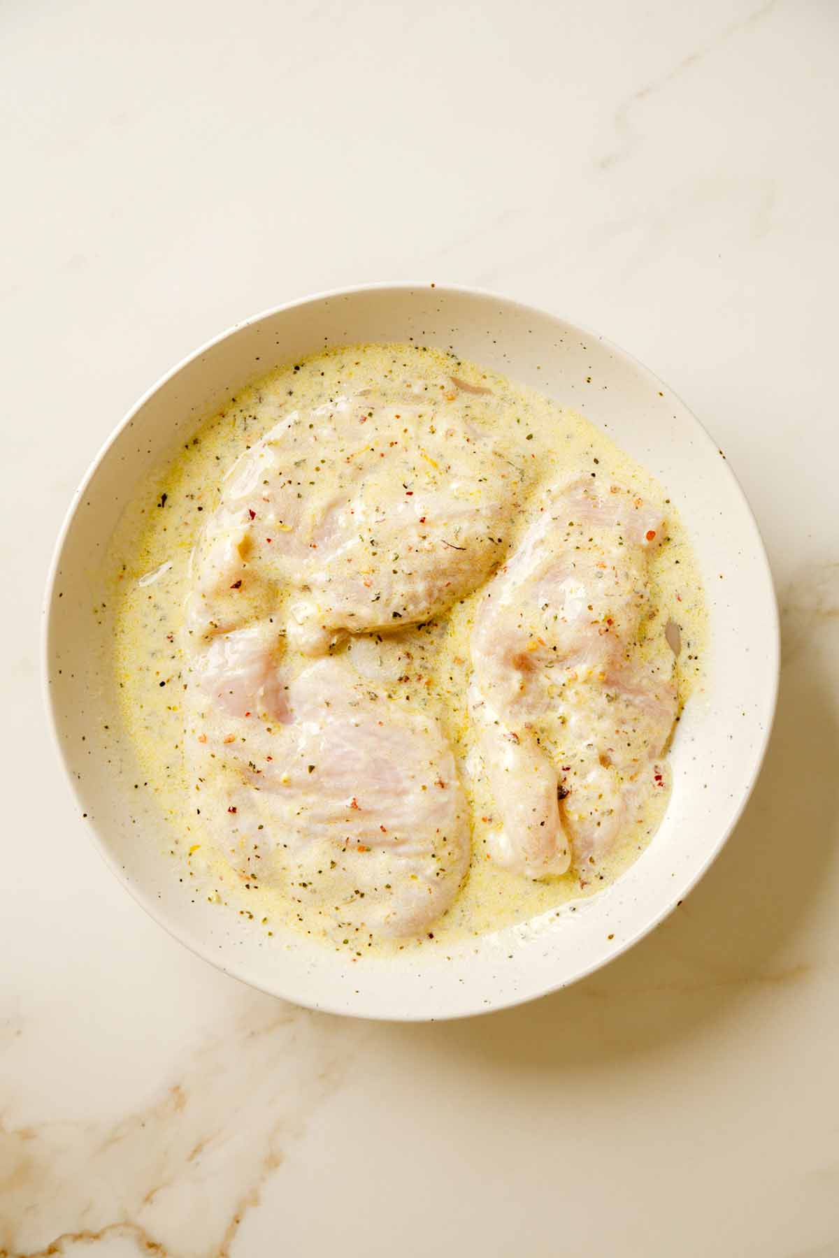 Greek Yogurt Marinade Poured over Chicken Breast