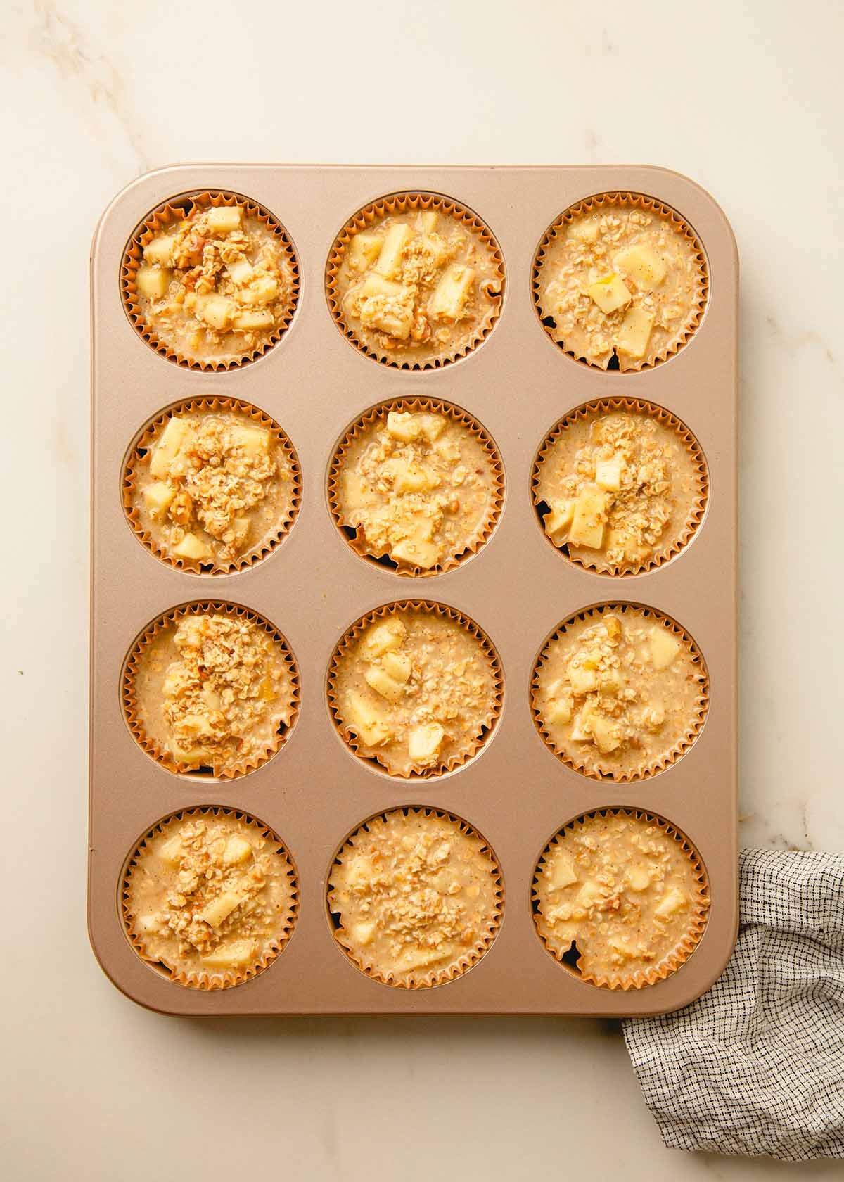 Muffin batter scooped into a lined muffin tin.