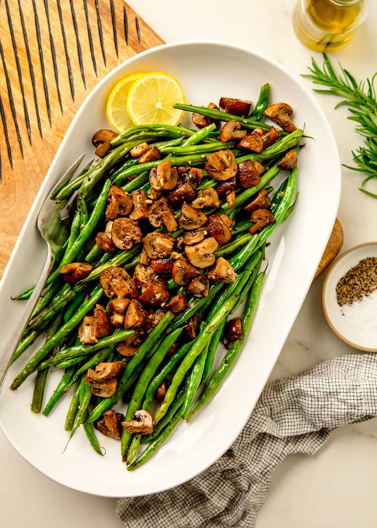 Roasted green beans with mushrooms and slices on lemon on a serving platter