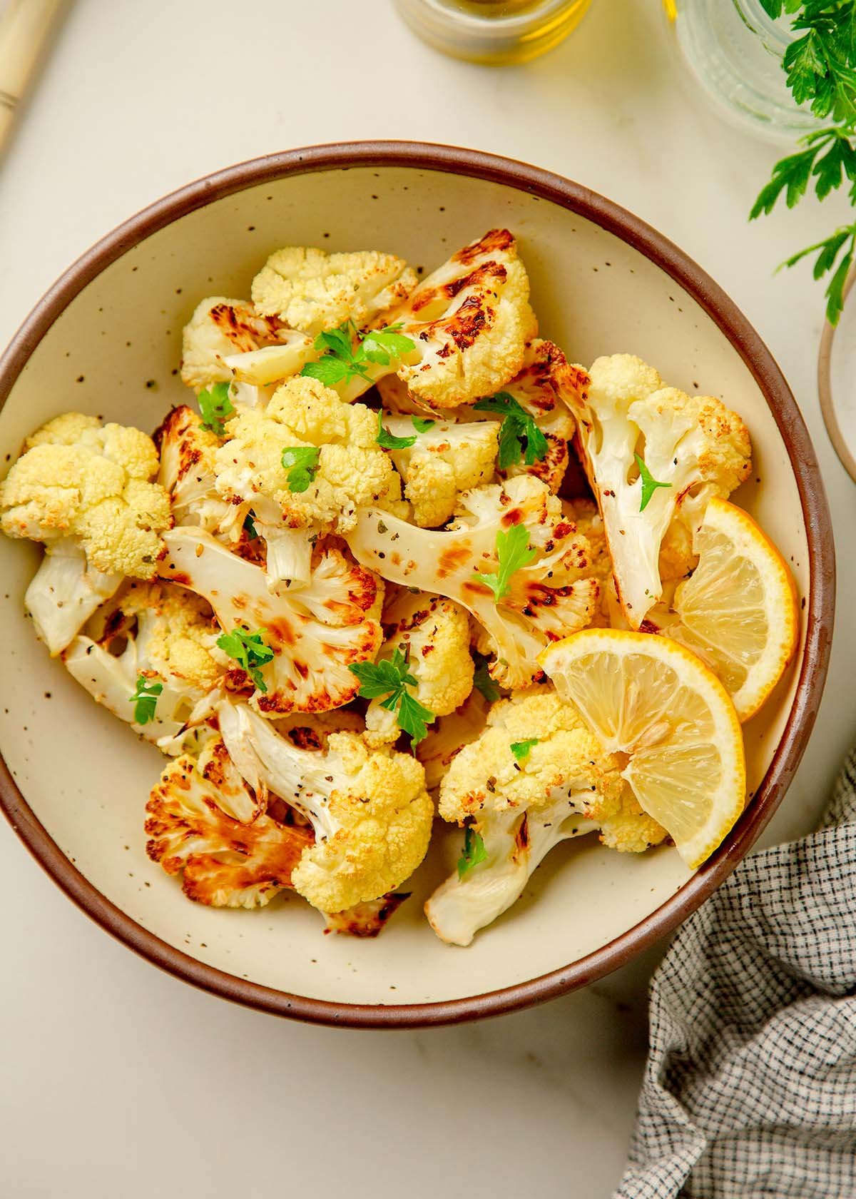 roasted cauliflower in a bowl with a side of lemon and herbs