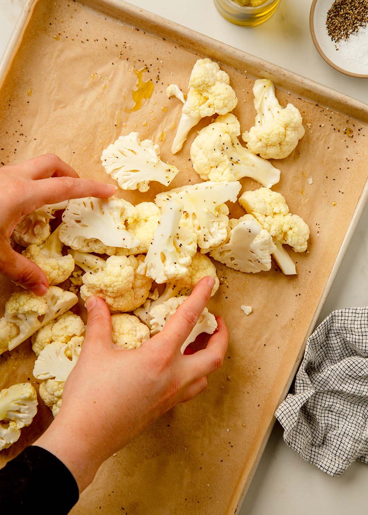 Cauliflower on a baking sheet tossed with olive oil, salt, and pepper