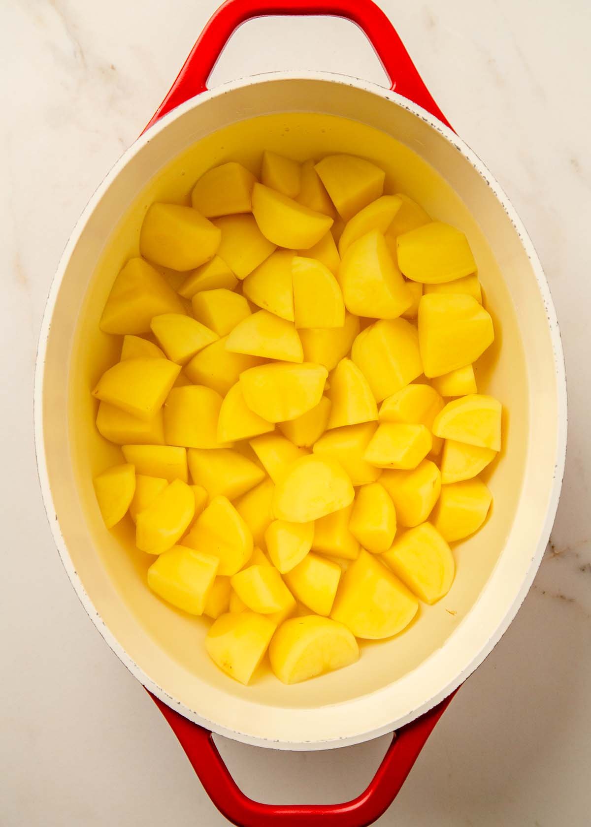 Chopped potatoes boiling in salted water in a large pot.