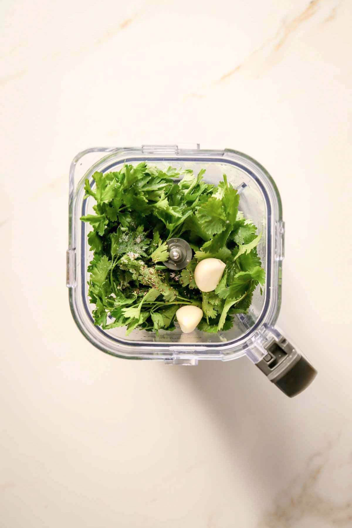 Placing the parsley, cilantro, garlic, lemon juice, salt, and pepper in a blender.
