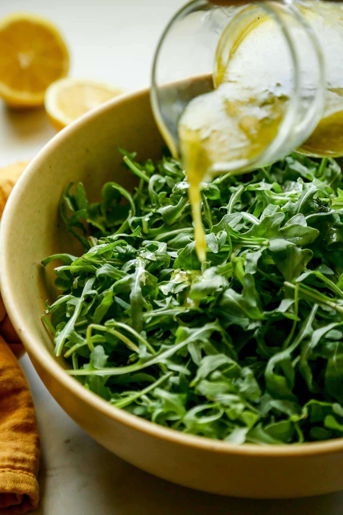 Lemon Dill Dressing Poured Over a Yellow Bowl of Fresh Arugula