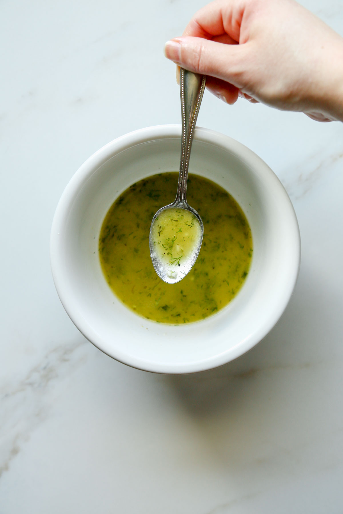 Lemon dill dressing in a bowl and a spoon showing the dressing 