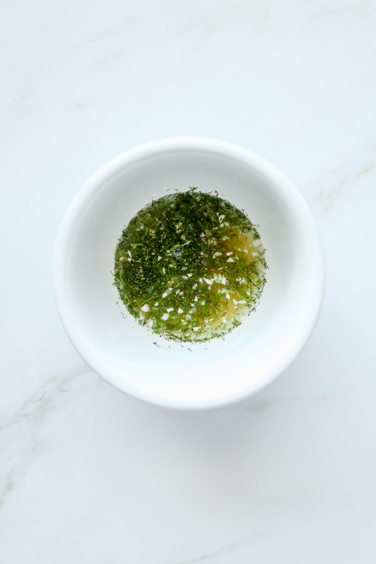 dill, garlic, lemon juice, vinegar in a white bowl before being mixed
