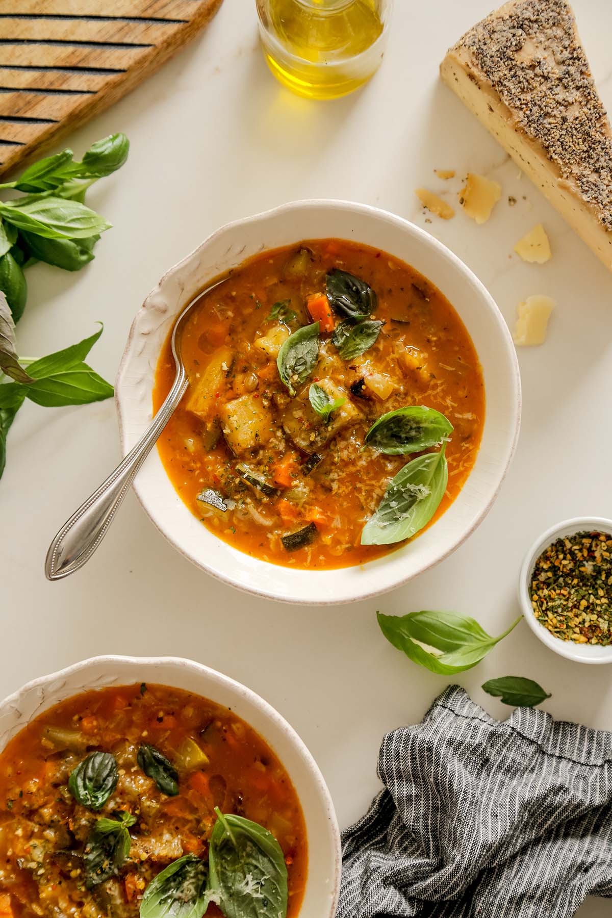 Two bowls of hearty roasted vegetable soup with a spoon in the top bowl.