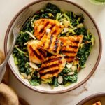 Overhead shot of Creamy Buffalo Kale Crunch Salad with Grilled Chicken Nuggets, featuring vibrant green kale and cabbage, golden-brown grilled chicken, and a creamy dressing drizzle.
