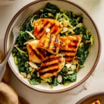 Overhead shot of Creamy Buffalo Kale Crunch Salad with Grilled Chicken Nuggets, featuring vibrant green kale and cabbage, golden-brown grilled chicken, and a creamy dressing drizzle.