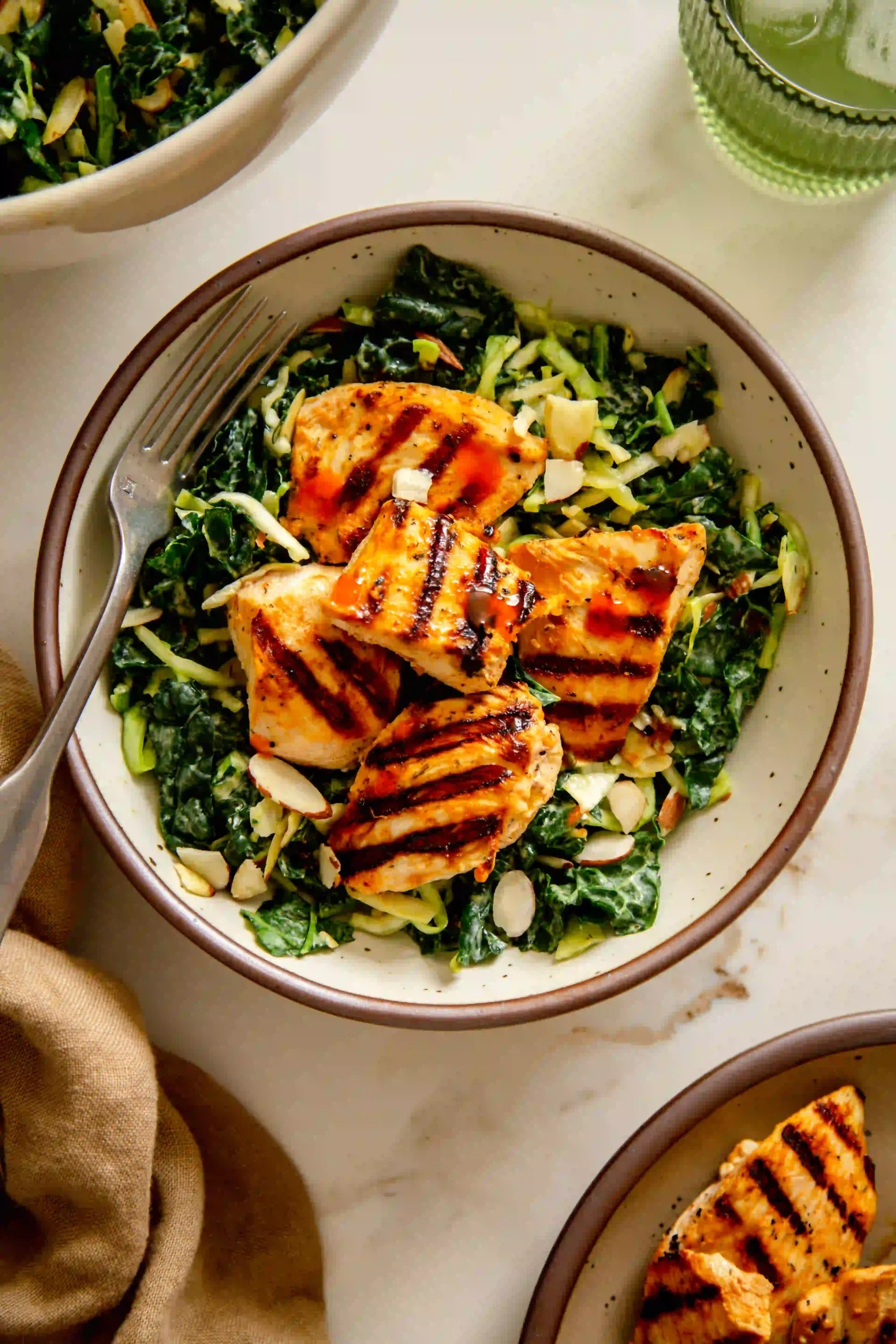 Overhead shot of Creamy Buffalo Kale Crunch Salad with Grilled Chicken Nuggets, featuring vibrant green kale and cabbage, golden-brown grilled chicken, and a creamy dressing drizzle.