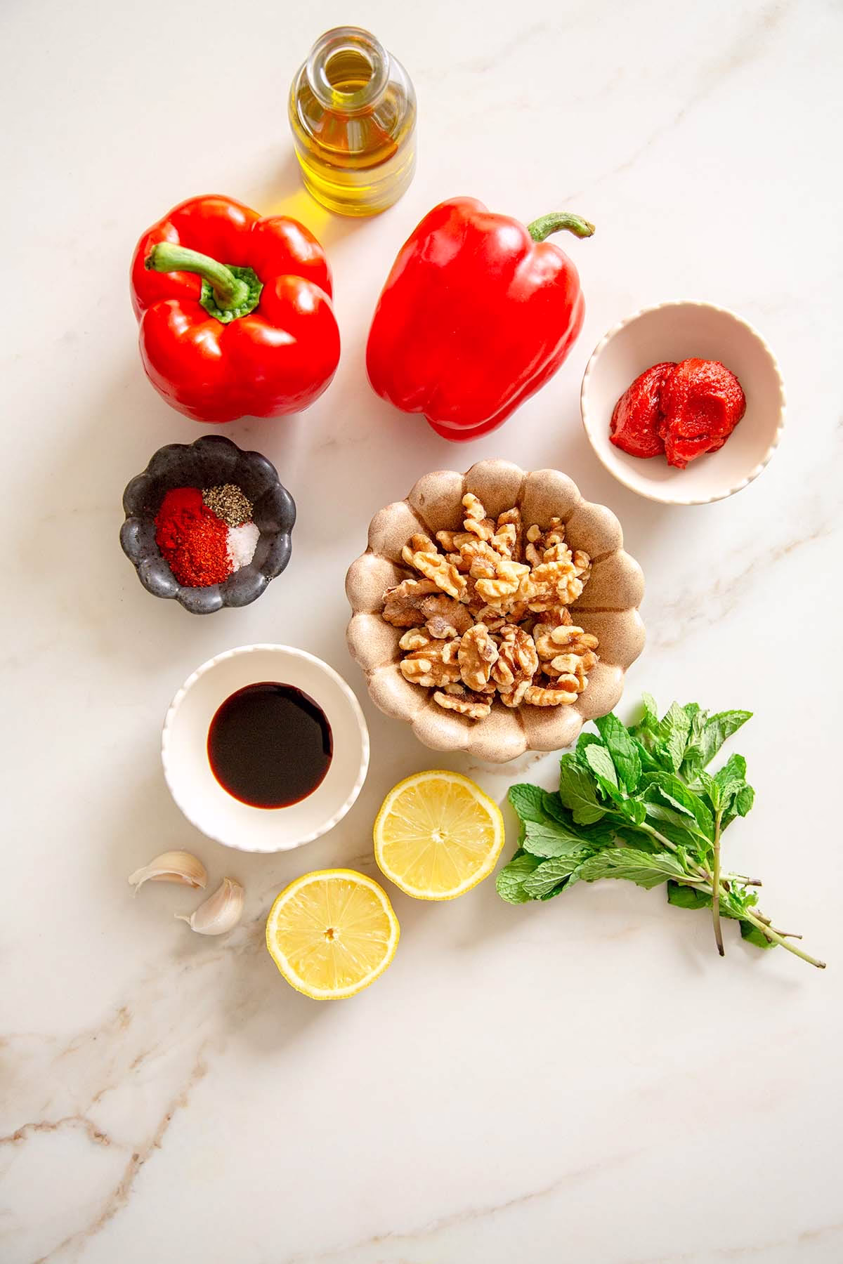 Ingredients for muhammara dip including roasted red peppers, walnuts, pomegranate molasses, olive oil, garlic, and spices