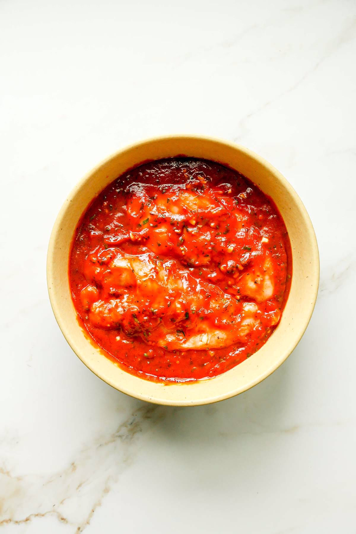 chicken breast marinating in a bowl