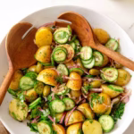 olive oil potato salad in a bowl with wooden spoons
