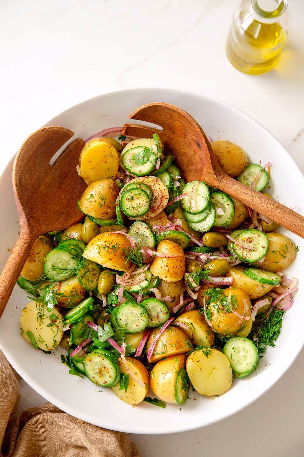 olive oil potato salad in a bowl with wooden spoons