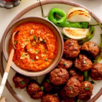 Roasted Mediterranean meatballs served with a bowl of smoky muhammara dip on the side