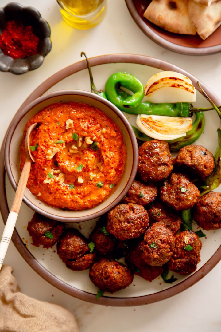 Roasted Mediterranean meatballs served with a bowl of smoky muhammara dip on the side