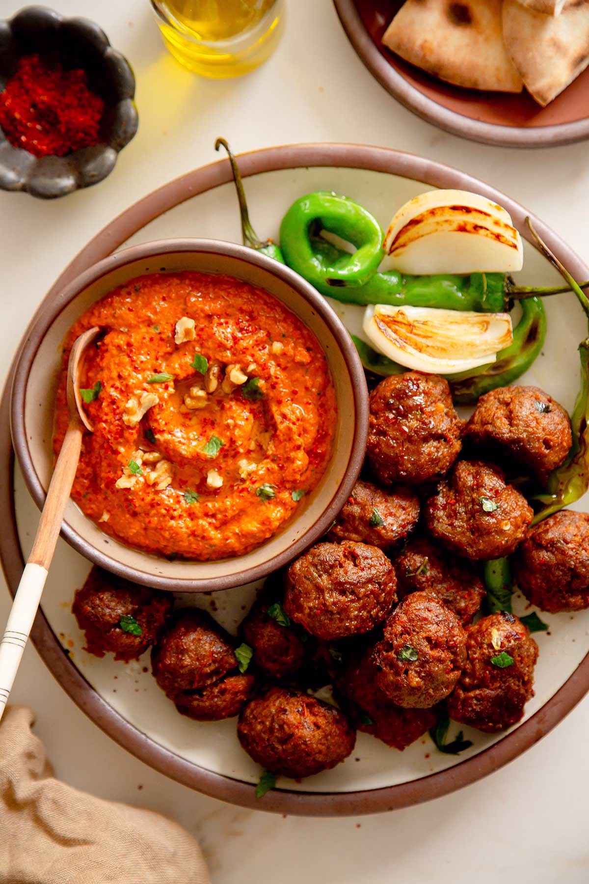 Roasted Mediterranean meatballs served with a bowl of smoky muhammara dip on the side
