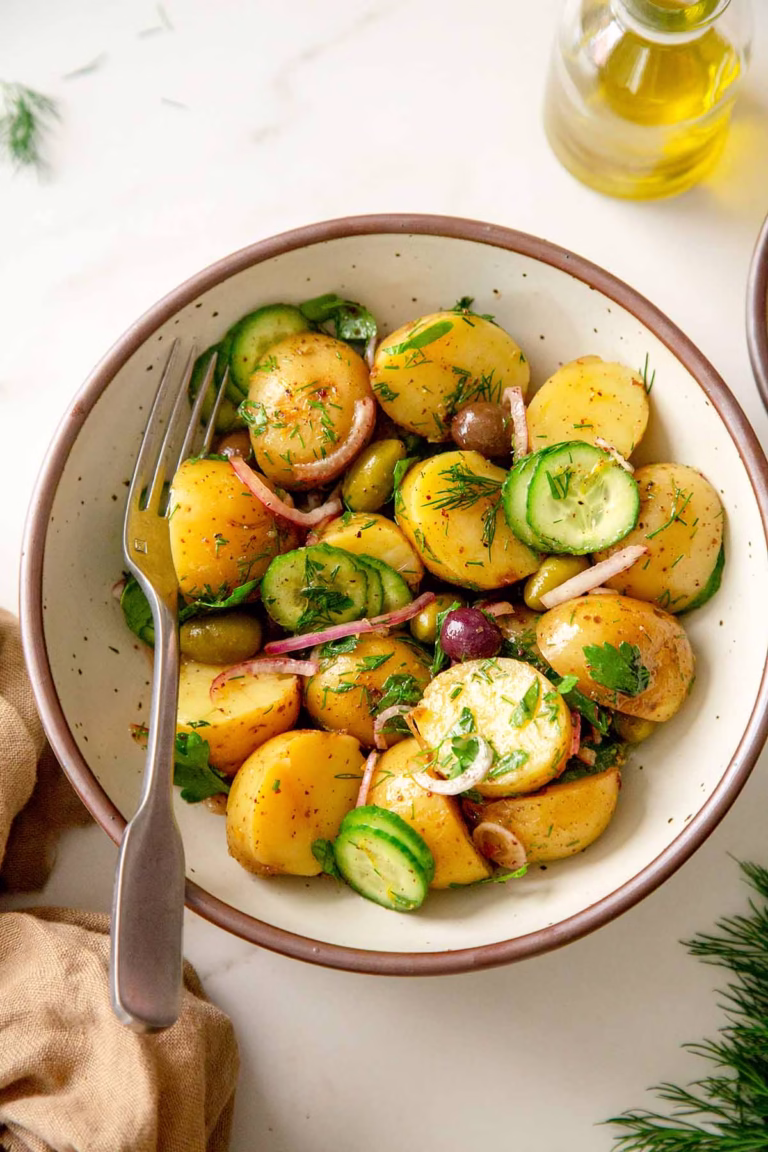 A bowl of zesty herb potato salad tossed in olive oil and sumac, garnished with fresh parsley and lemon zest