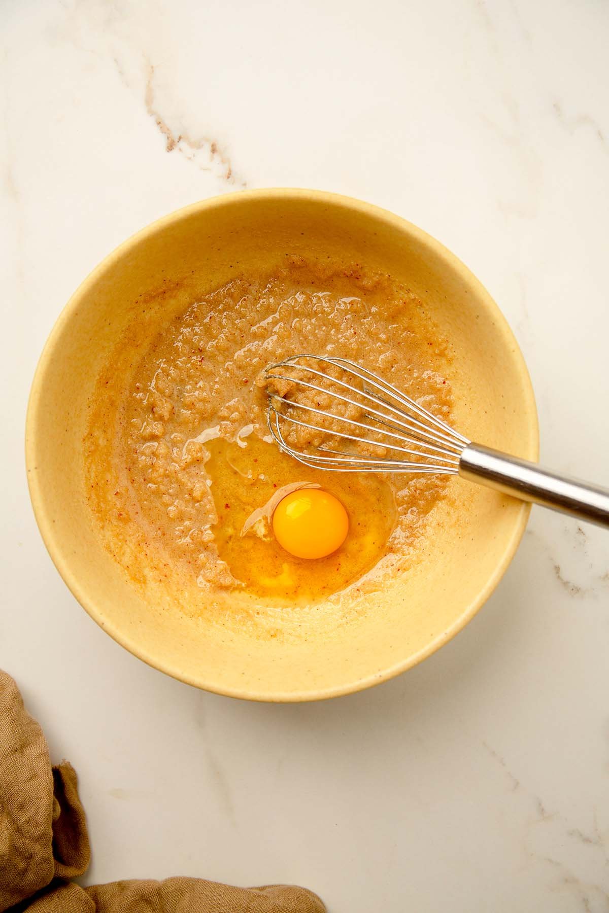 Adding egg to wet ingredients in large yellow bowl