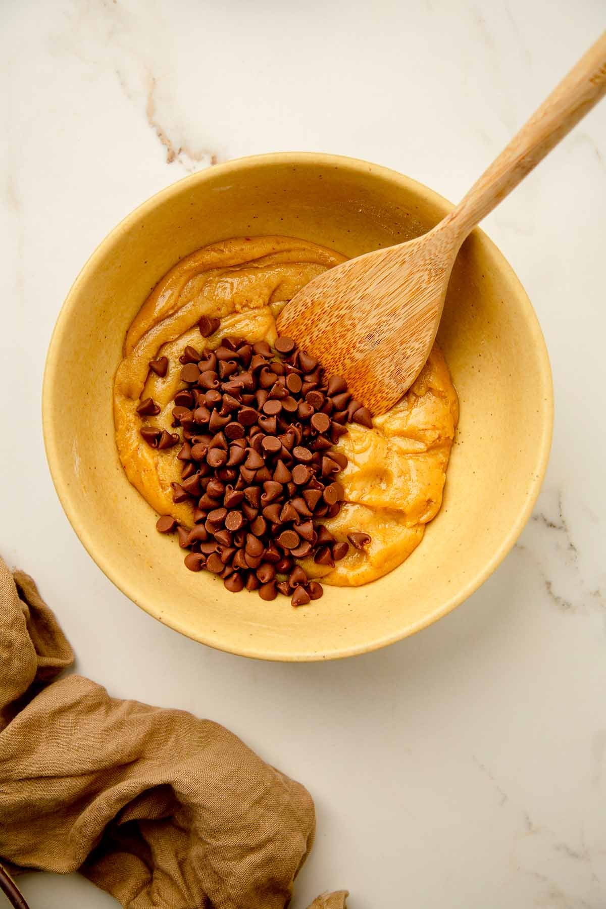 Chocolate chips over cookie batter in a bowl