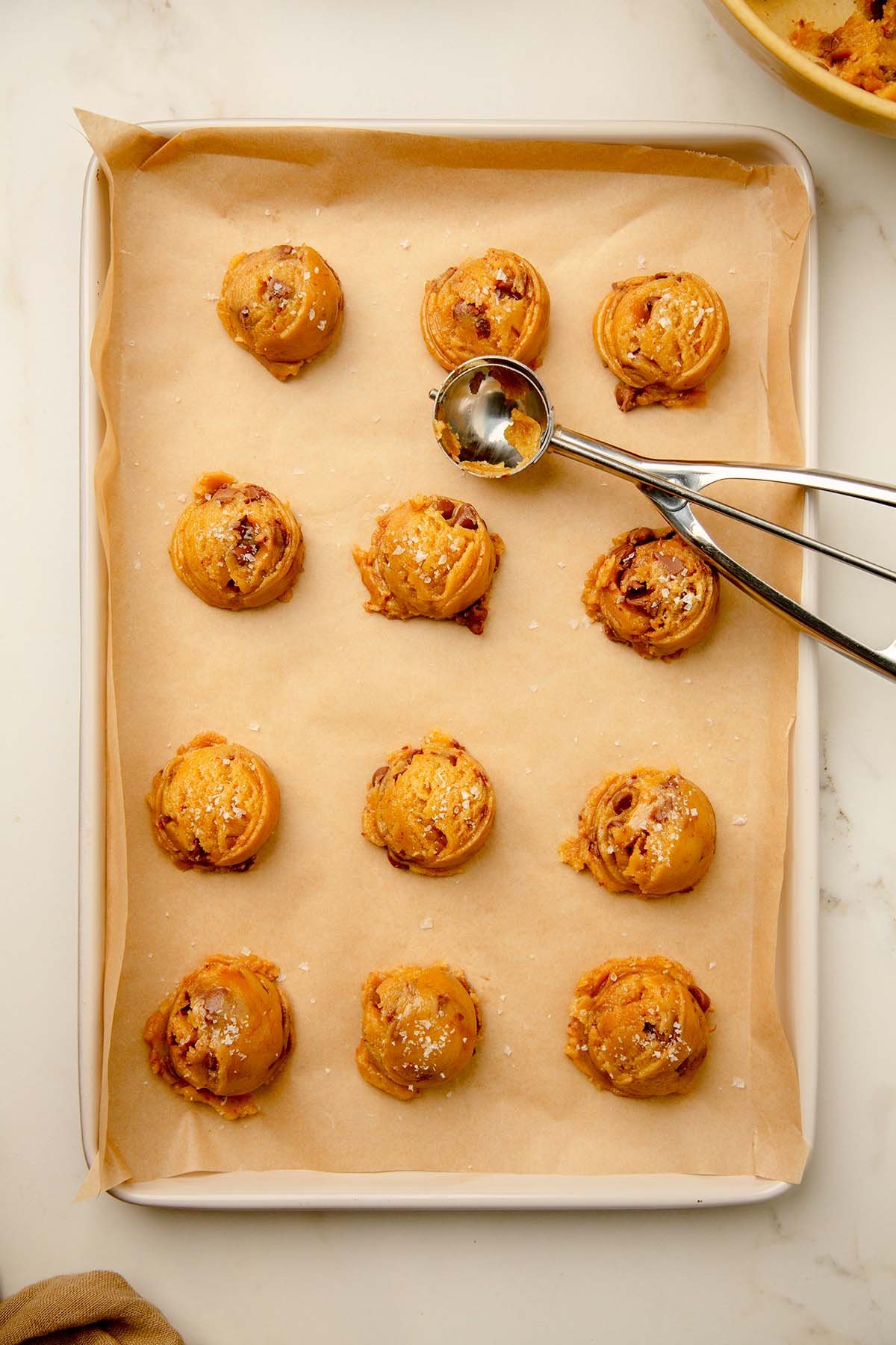 Scooped tahini chocolate chip cookie dough on a cookie sheet