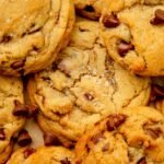 Close-up of golden-brown tahini chocolate chip cookies topped with flaky sea salt