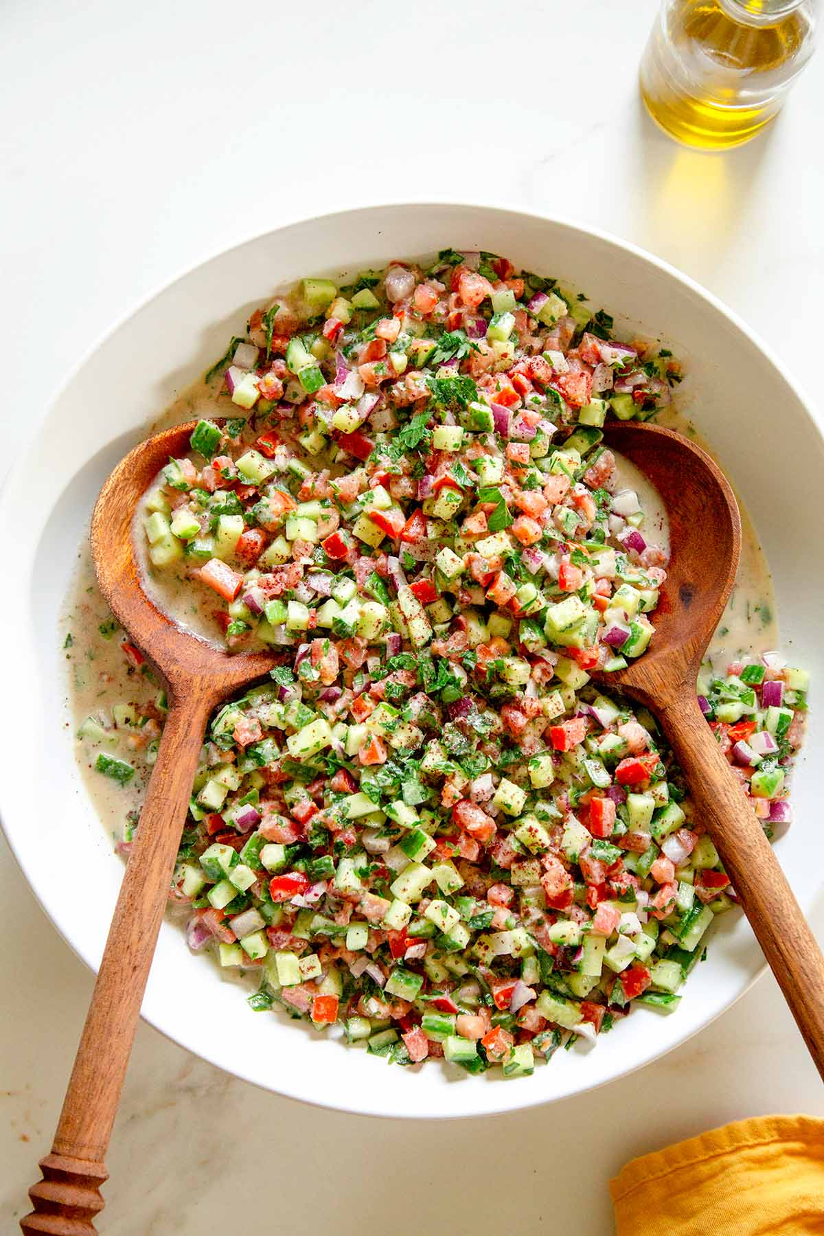 Tahini Salad in a white bowl with two wooden spoons