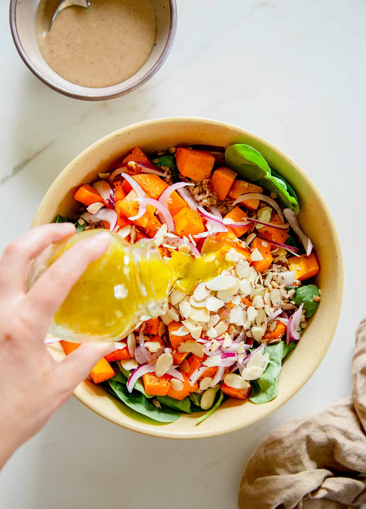pouring lemon dressing over squash salad
