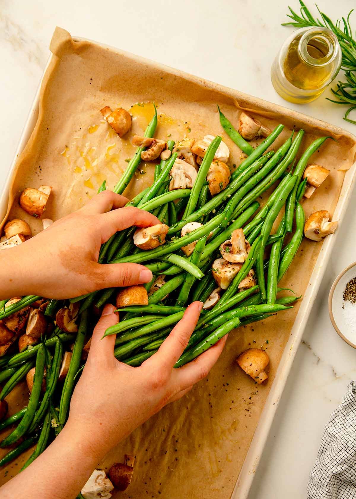 Tossing green beans and mushrooms on sheet pan