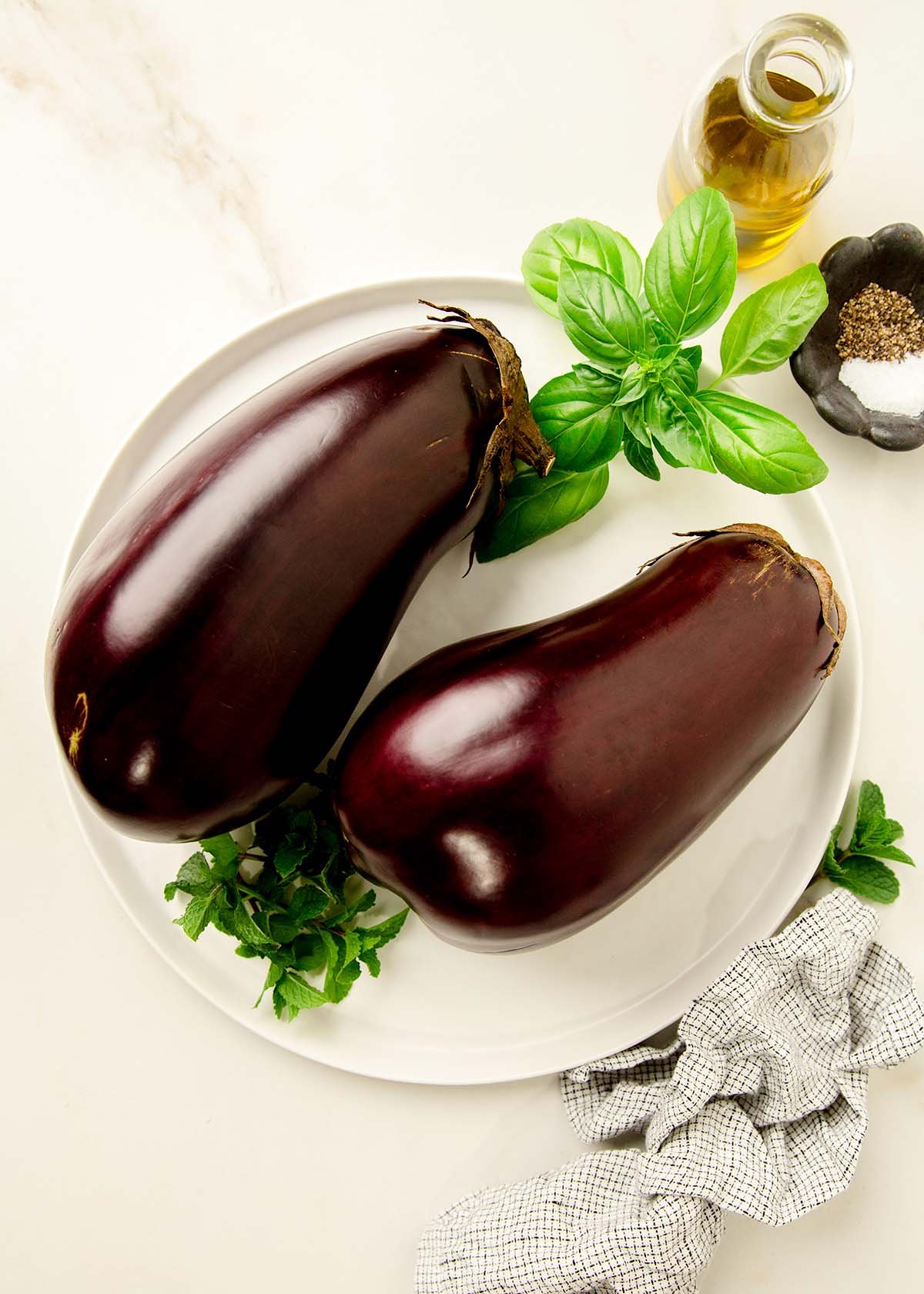 Ingredients to make roasted eggplant; olive oil, salt, pepper, and eggplant