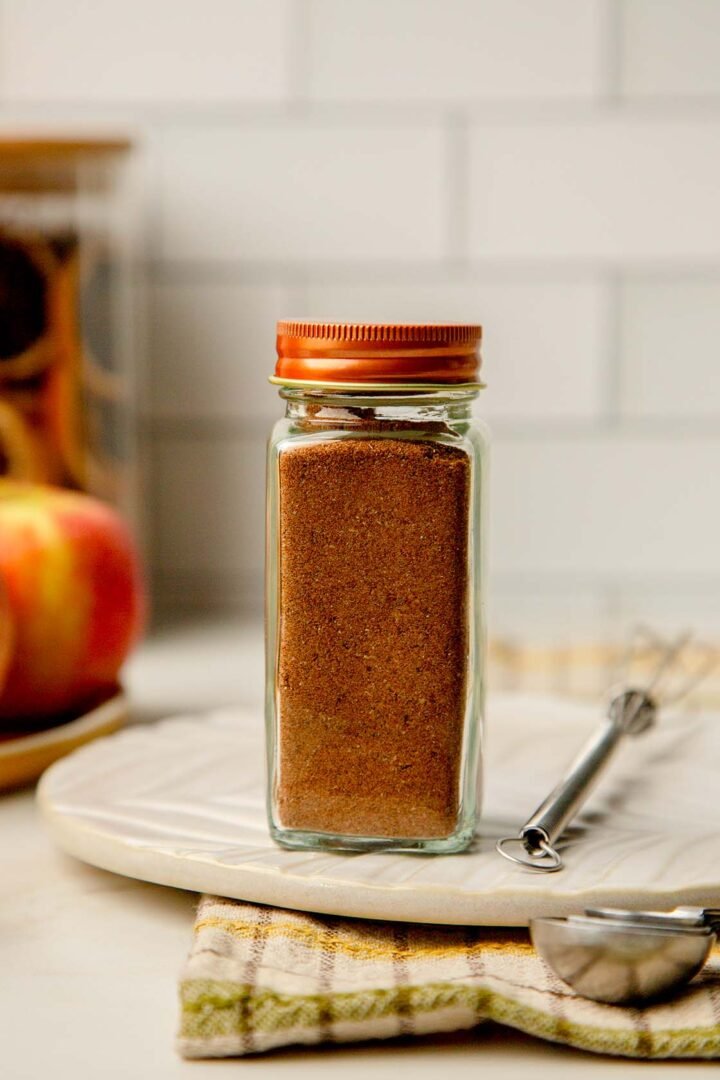 Small glass spice jar filled with Mediterranean Sweet Spice Blend with warm golden tones.