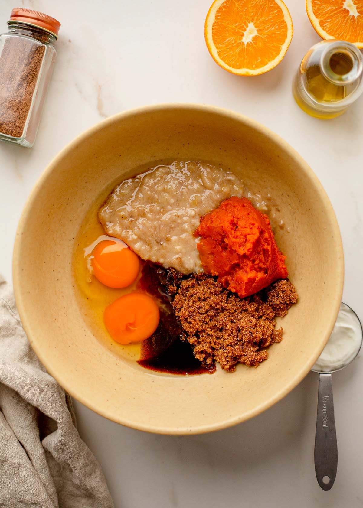 Wet Ingredients in a bowl; two eggs, mashed banana, pumpkin puree, brown sugar, and vanilla bean paste in a yellow bowl