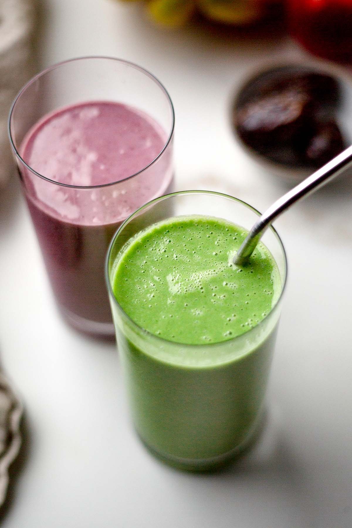 Berries and cream smoothie in a glass with green tropical smoothie in a glass