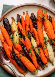 Roasted Rainbow Carrots on a plate garnished with shallot honey jam and fresh parsley