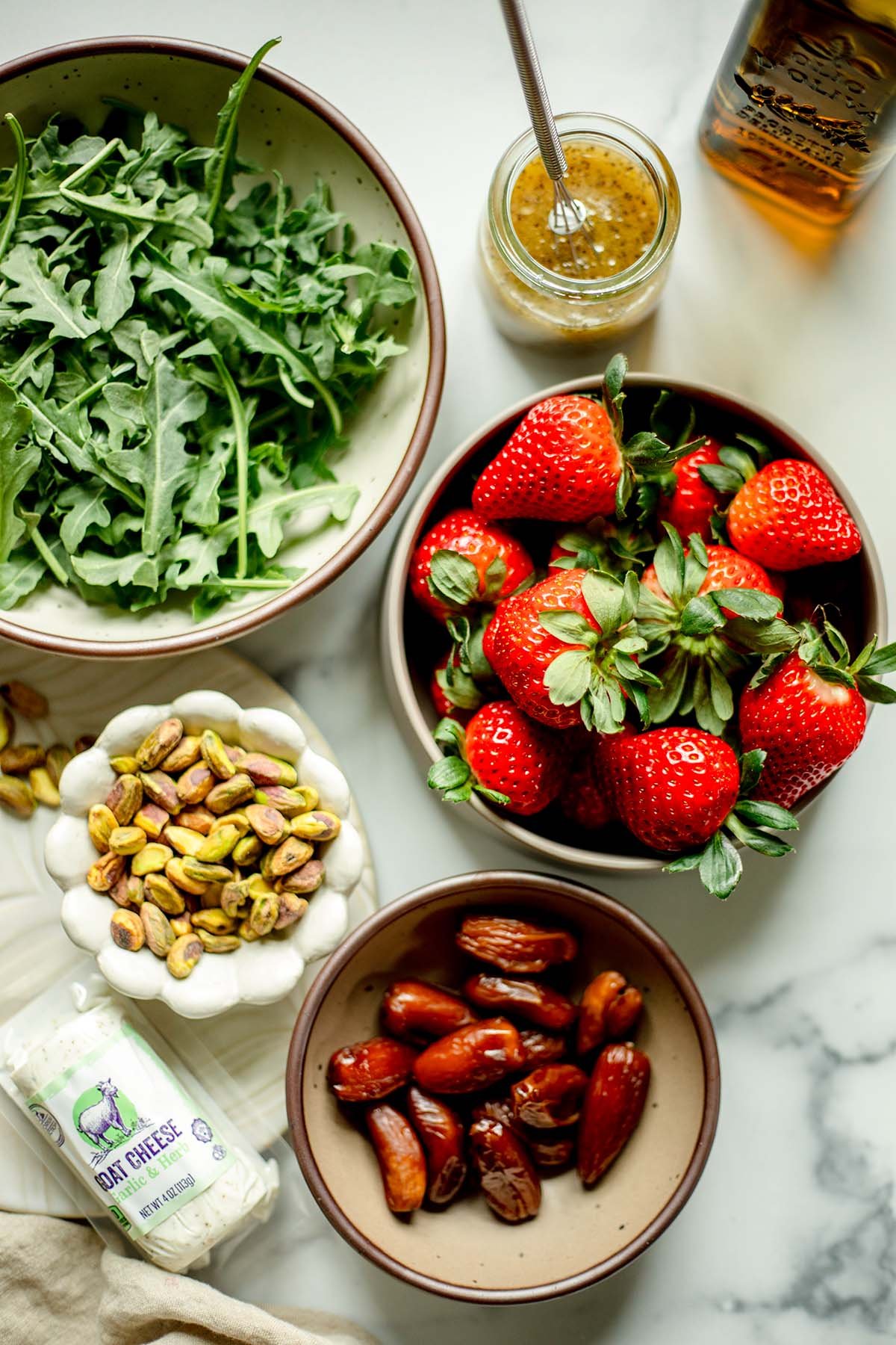 Arugula, strawberries, dates, pistachios, goat cheese, poppy seed vinaigrette dished up in bowls