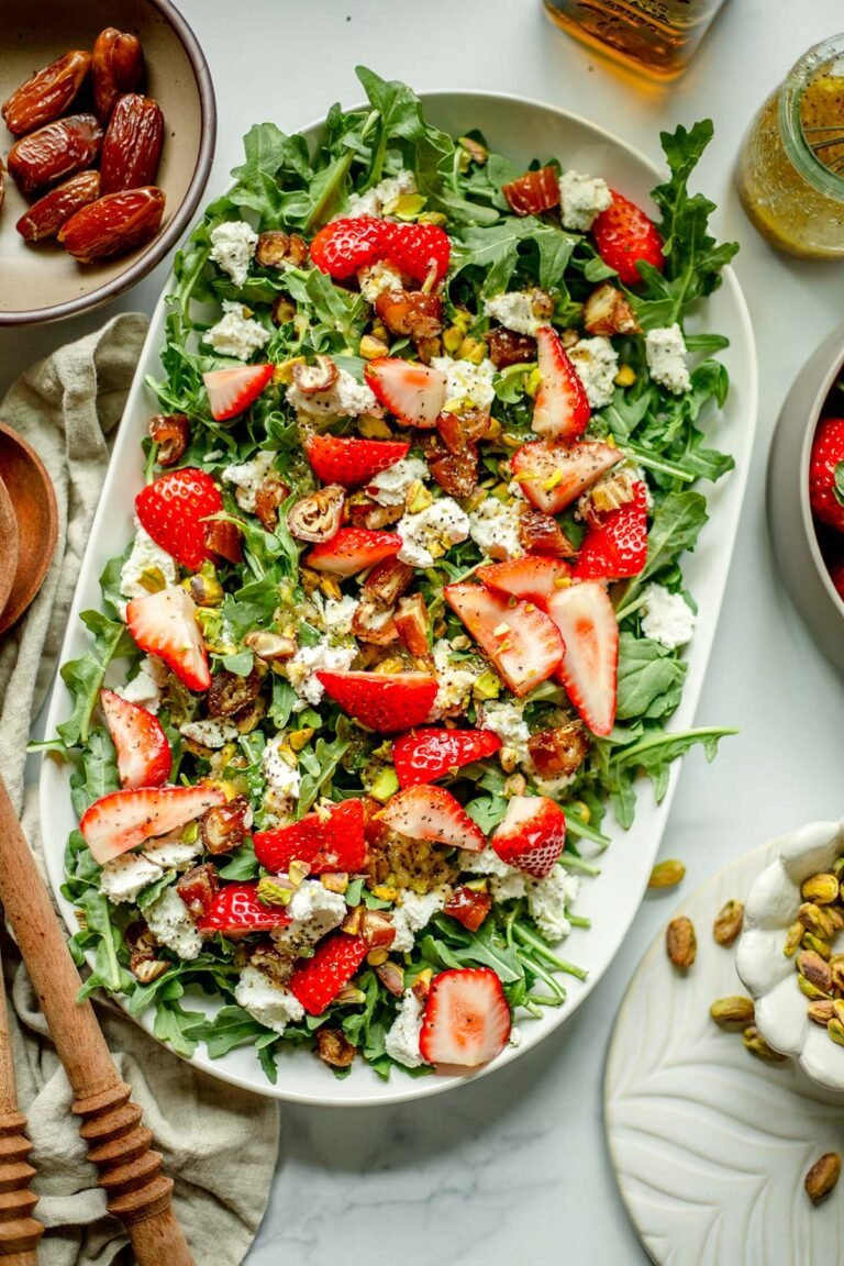 Strawberry Arugula Salad with a bowl of pistachios, strawberries, and wooden spoons