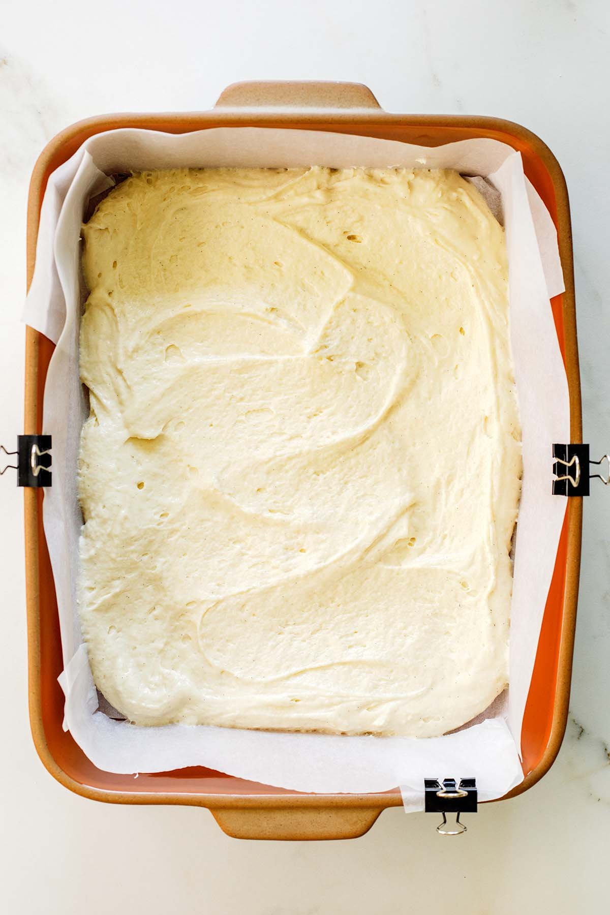 Thick Greek yogurt coffee cake batter spread evenly into a parchment-lined 9x13 baking pan.