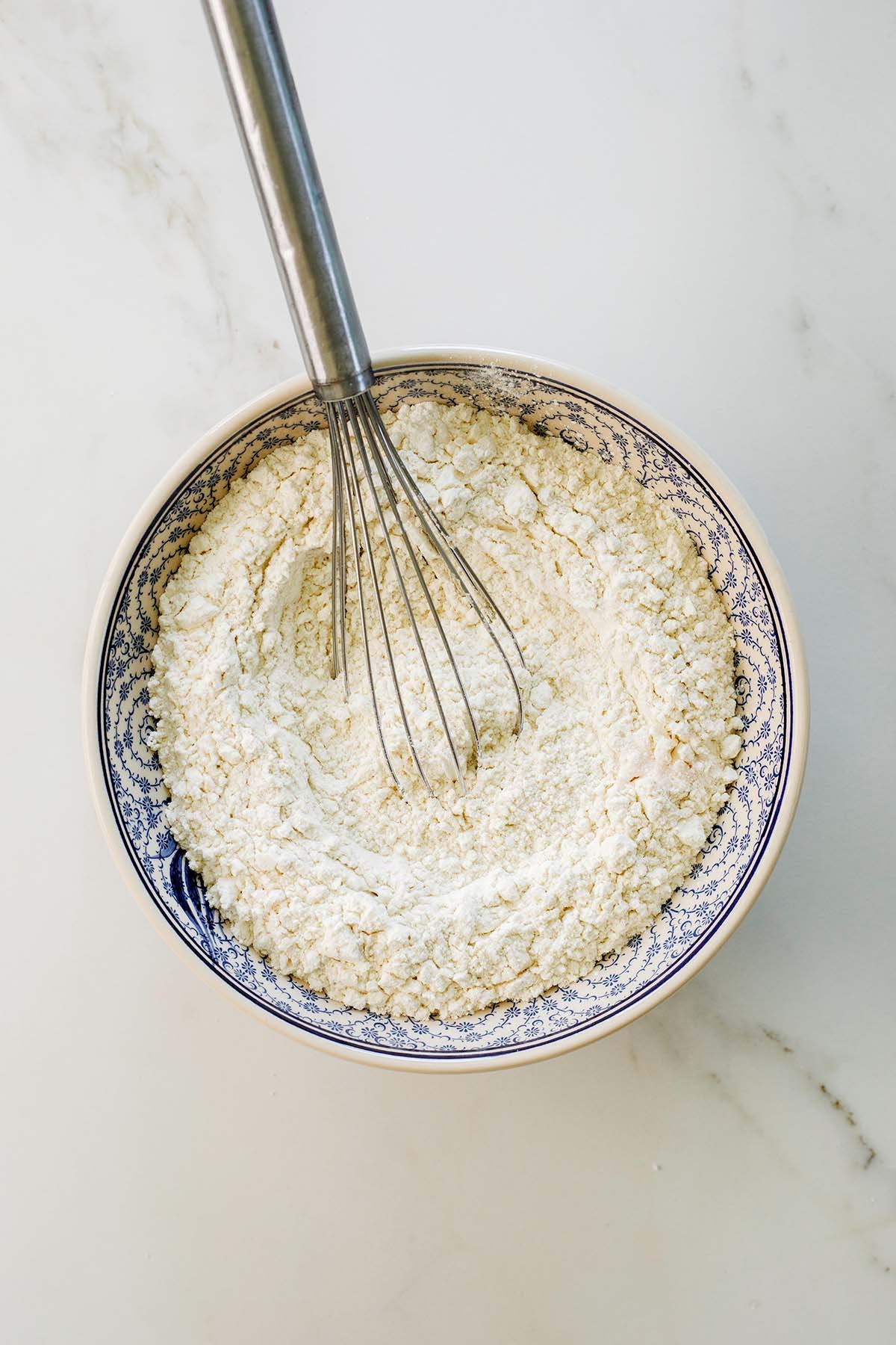Flour, baking powder, and baking soda whisked together in a bowl for Greek yogurt coffee cake
batter.